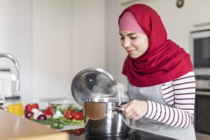 joyful muslim woman checking pot on stove cooking 2025 03 18 18 47 28 utc