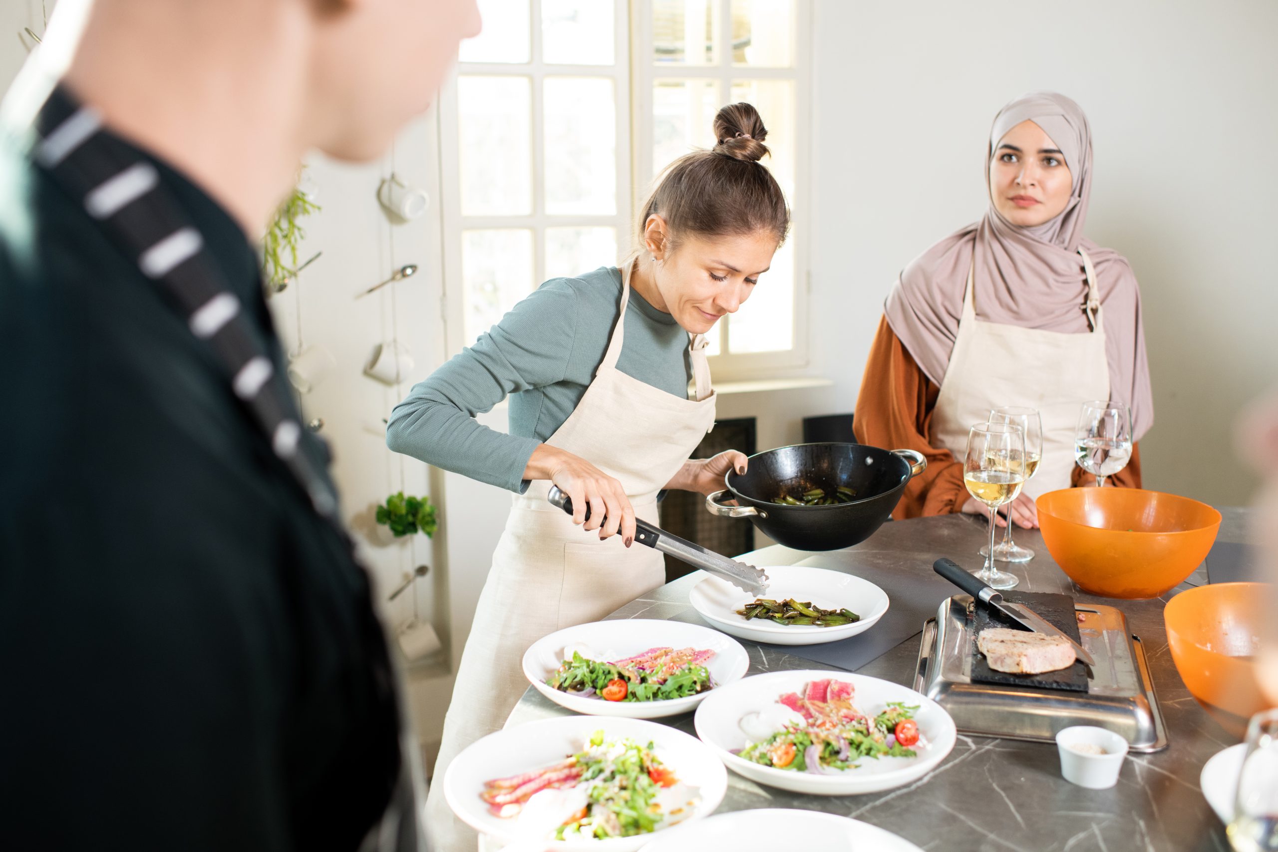 Best Halal Cooking Classes You Can Attend Around the World 7 young female with frying pan bending over large ki 2025 03 14 07 59 26 utc scaled