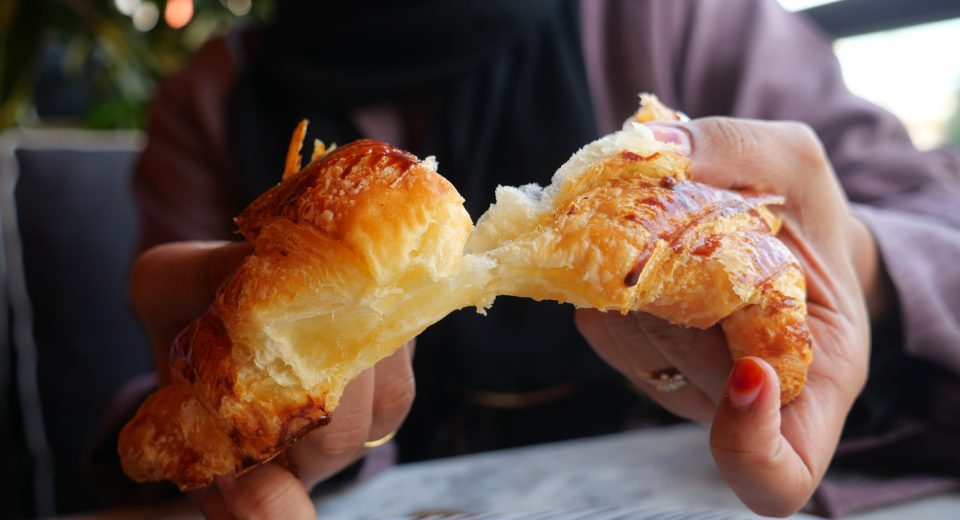 closeup of hand breaking a croissant bun 2024 12 13 14 23 09 utc