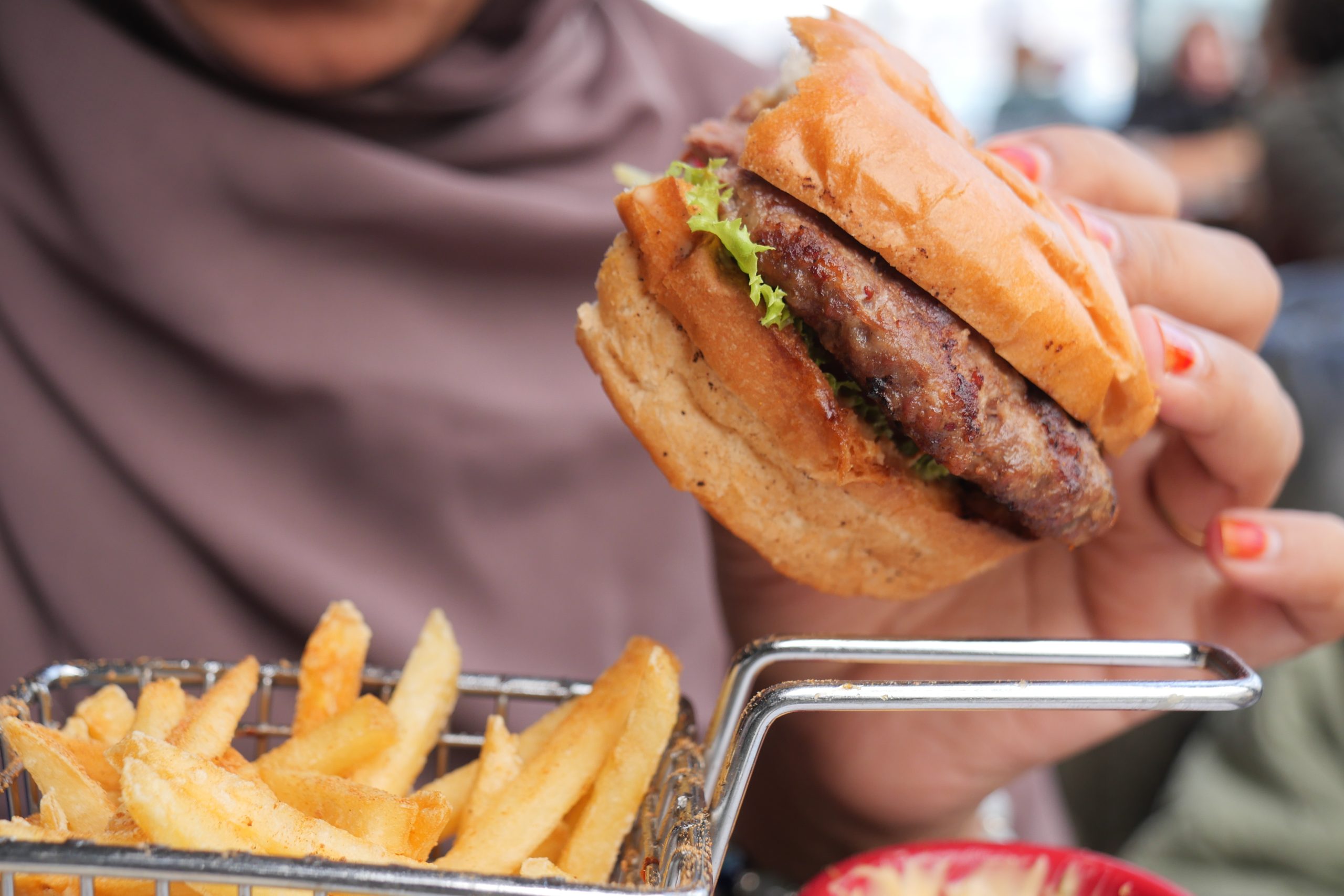 woman hand holding a beef burger enjoying her meal 2024 12 13 14 46 24 utc scaled
